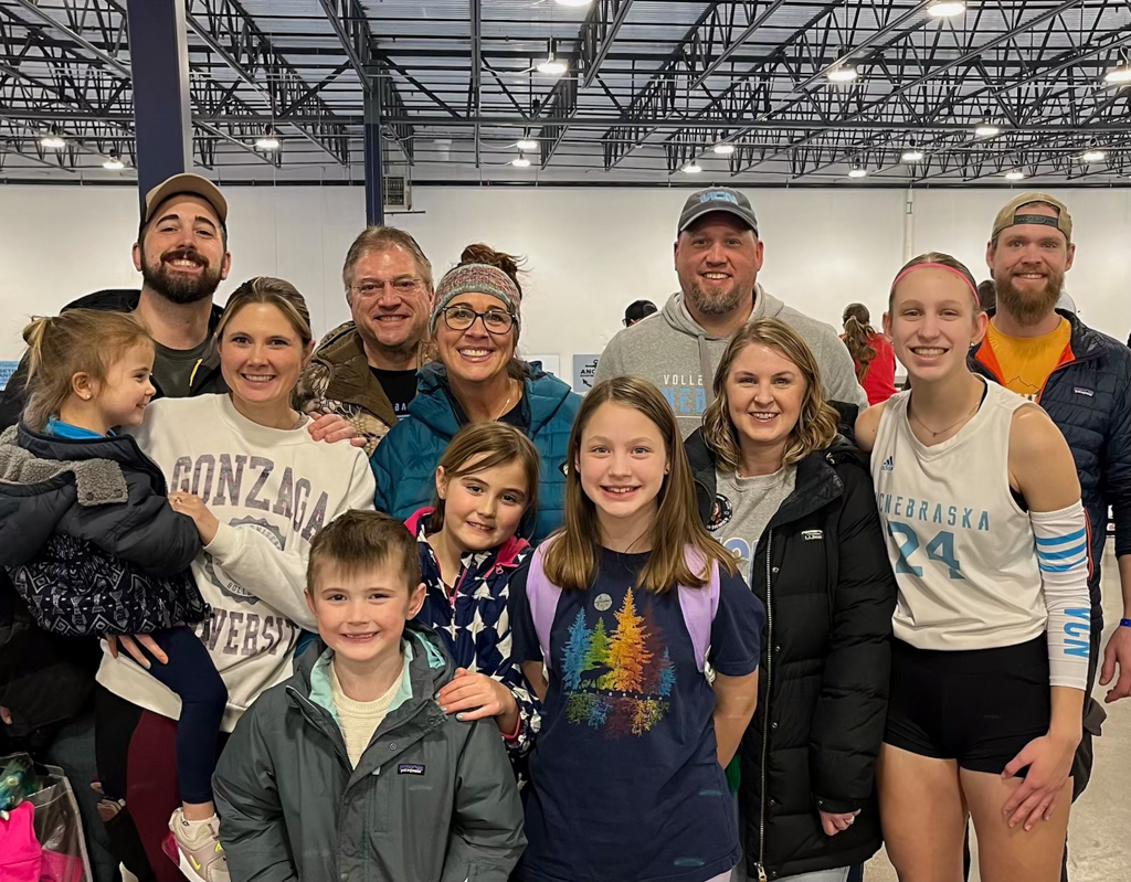 Extended family group photo smiling while supporting volleyball player at a club tournament