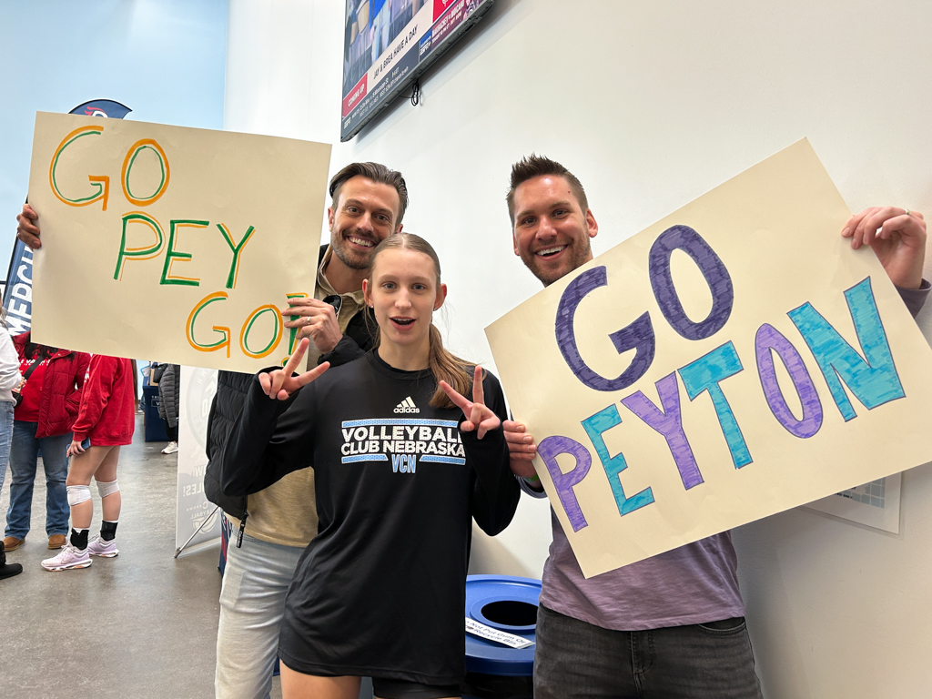 Smiling volleyball player with two fans holding up signs