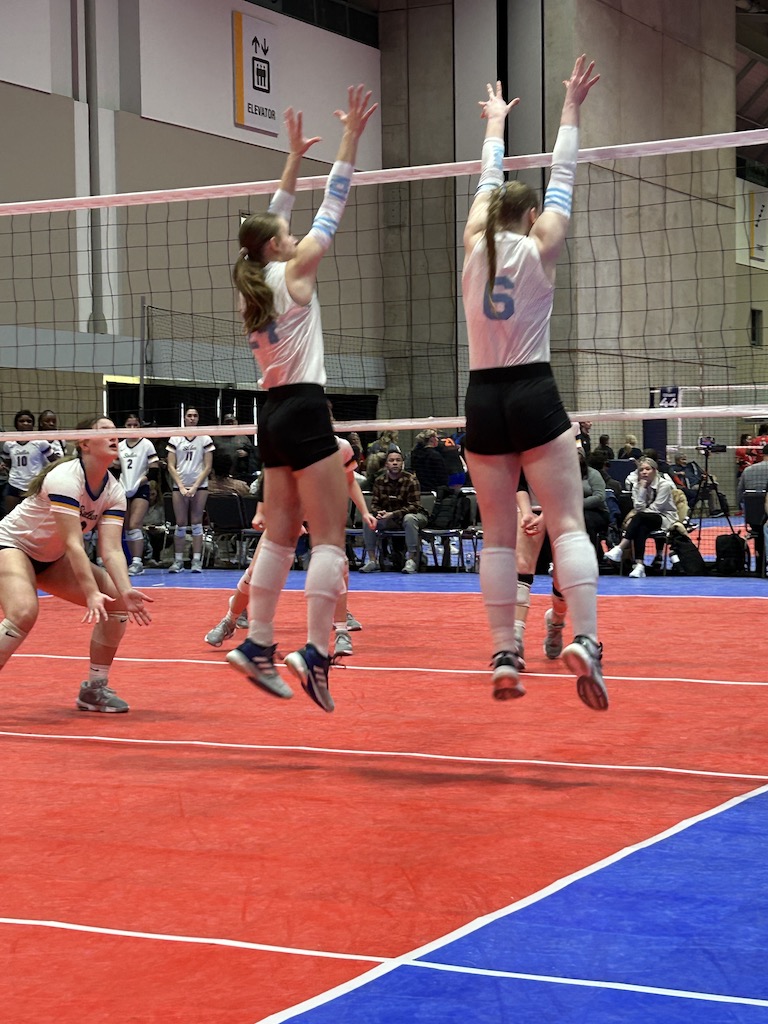 Two volleyball players going up for a block