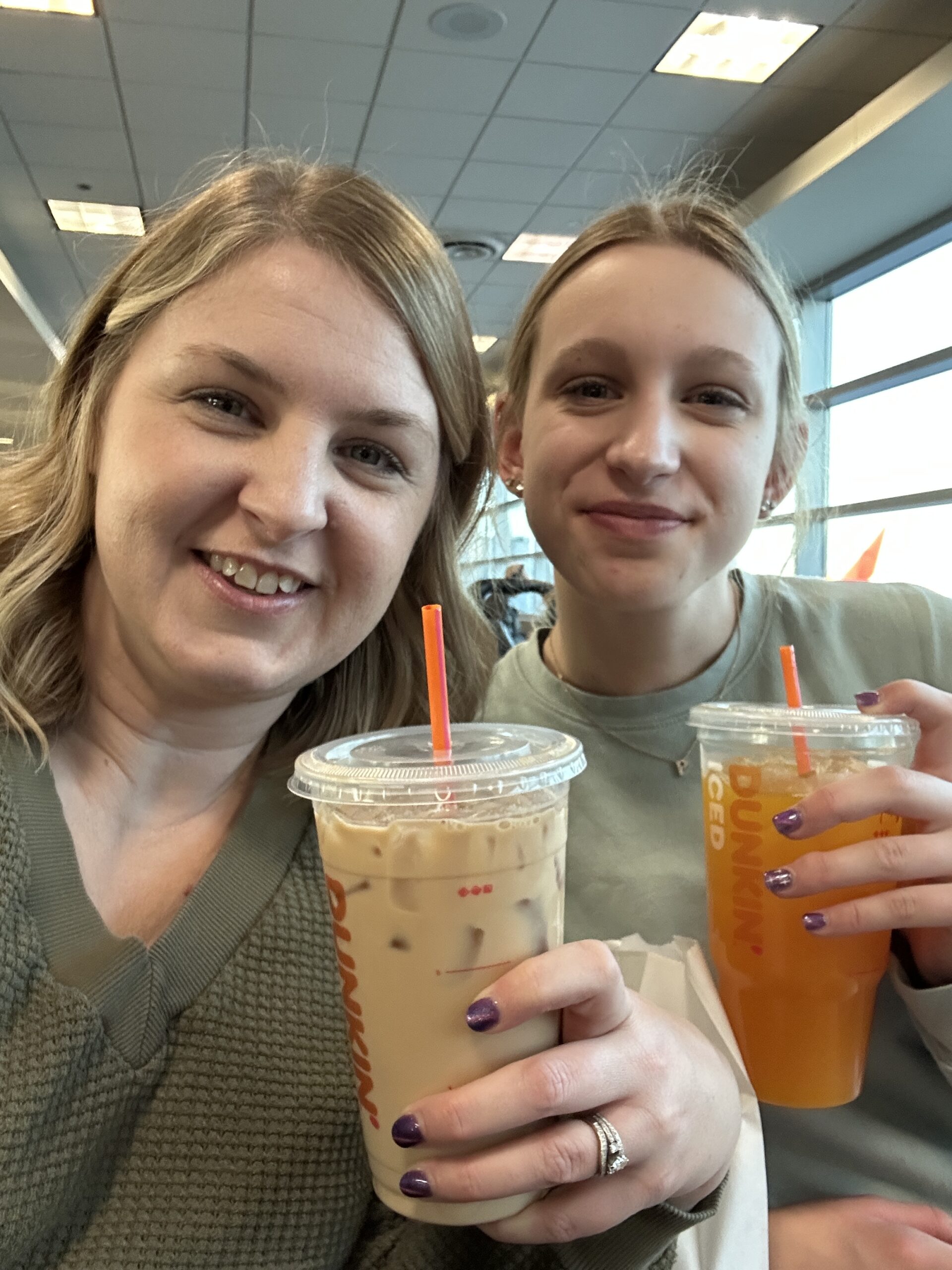 Mom and daughter with drinks from Dunkin' sitting in the airport